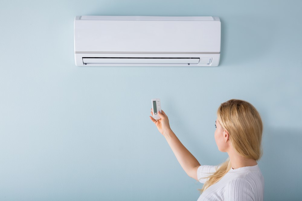A woman lights a wall air conditioner